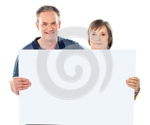 Smiling aged couple displaying blank banner