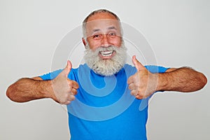 Smiling aged man giving two thumbs up against white background