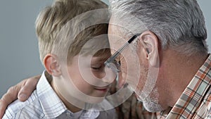 Smiling aged man hugging grandson with love, generations connection, closeness