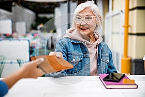 Smiling aged woman giving bill to waitress stock photo