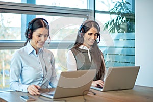 Smiling agent woman with headsets. Portrait of call center worker at office.