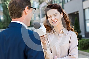 smiling anchorwoman with microphone interviewing