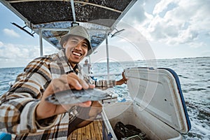 smiling angler showing fish for sea fishing in a boat