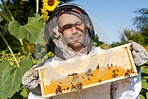 smiling apiarist in beekeeping suit holding