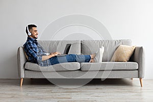 Smiling Arab man in headphones using pc at home