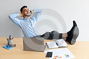 Smiling Arab man leaning back sitting at desk