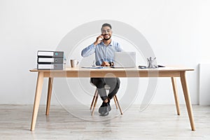 Smiling Arab man working and talking on phone at home