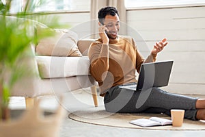 Smiling Arab man working and talking on phone at home