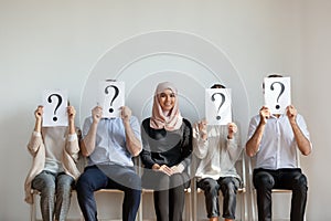 Smiling Arabian hired employee sit among people holding paper sheets