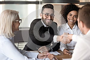 Smiling Arabian male employee handshake colleague at meeting