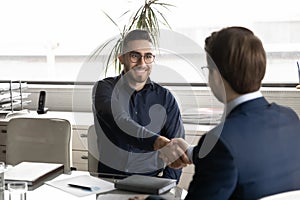 Smiling Arabic businessman handshake male partner at office meeting