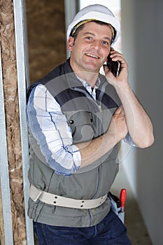 Smiling architect with safety helmet on phone