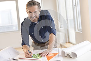 Smiling Architect Working On Blueprint At Desk