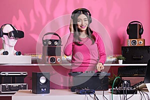 Smiling artist standing at dj table playing techno music at professional mixer console in studio