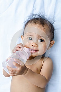 Smiling Asian baby girl drinking water from bottle