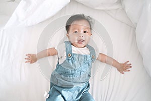 Smiling asian baby girl lying on a bed.