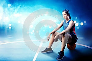 Smiling asian basketball player woman sitting on the ball