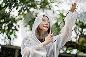Smiling Asian beautiful woman hold on umbrella with happy with rain