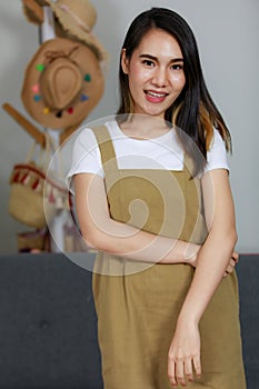 Smiling asian beautiful woman Standing wearing a brown dress In a home sales room. Female asia smlie in white background