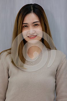 Smiling asian beautiful woman Standing wearing a Gray dress in the bedroom behind a curtain. Female asia smlie in gray background