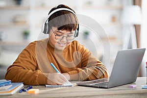 Smiling asian boy schooler having online lesson from home