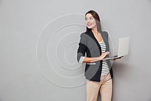 Smiling asian business woman holding laptop computer and looking back