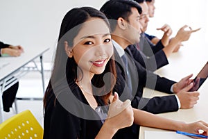 Smiling Asian business woman is thumbs up for good seminar course and marketing knowledge planning in classroom with