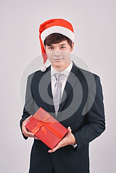 Smiling asian businessman in santa hat presenting gift isolated