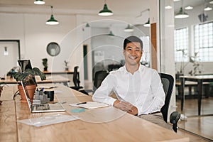 Smiling Asian businessman working at his desk in an office