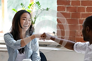 Smiling Asian businesswoman with African American colleague fists bump