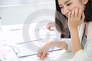 Smiling asian businesswoman looking at document paper at team meeting, happy attentive female team leader listening to new project