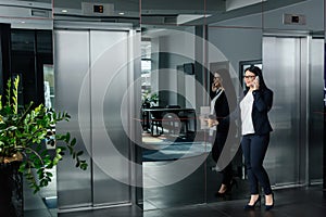 Asian businesswoman pushing button of elevator