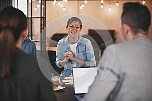 Smiling Asian businesswoman talking to coworkers during a meetin
