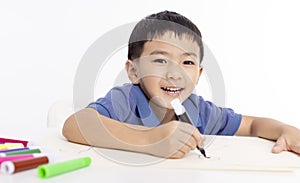 Smiling asian child schoolboy studying and drawing at home