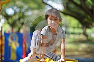 Smiling asian chinese girl climbed to the top of playground obstacles