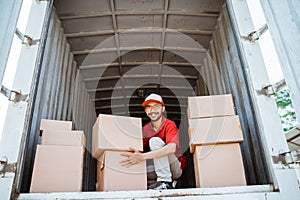 Smiling asian delivery man going to lift package box