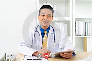 Smiling Asian doctor with digital tablet looking at camera. Remote online medical chat consultation, tele medicine distance photo