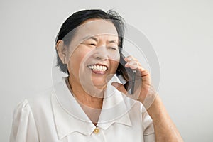 Smiling Asian elderly woman while talking on mobile phone showing happy mood