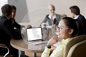 Smiling Asian employee distracted from meeting dreaming of somet