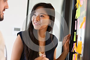 Smiling Asian female brainstorm using memo pads in office