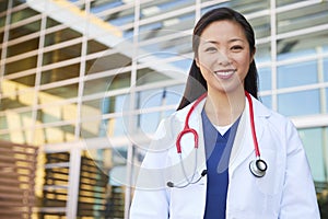 Smiling Asian female healthcare worker outdoors in lab coat