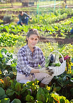 Smiling asian female holding vegetables grown in home garden