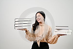 Smiling Asian female teacher holding a stack of books, isolated white background