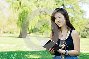 Smiling asian girl reading a book