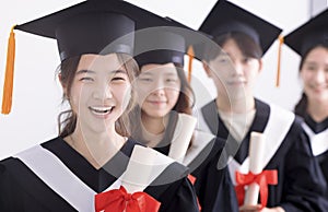 Smiling asian girl student  graduate and classmates standing with diplomas in hands