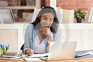 Smiling asian girl student study in library with laptop books