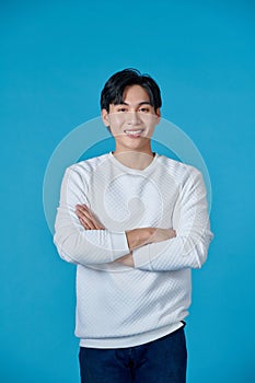 Smiling asian guy looking happy at camera, cross arms chest confident