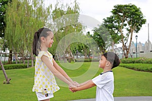 Smiling Asian little boy and girl child with hand in hand while playing together in the garden
