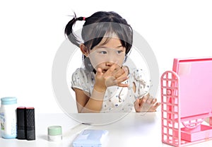 Smiling asian little girl is applying make up baby powder her fa