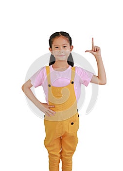 Smiling Asian little girl kid pointing finger up and looking at the camera isolated over white background. Idea, warning and